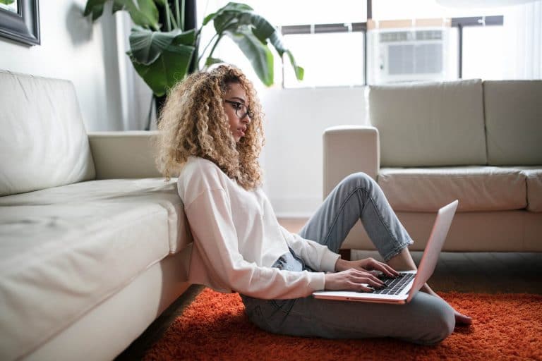 woman on the floor near a couch using a laptop computer