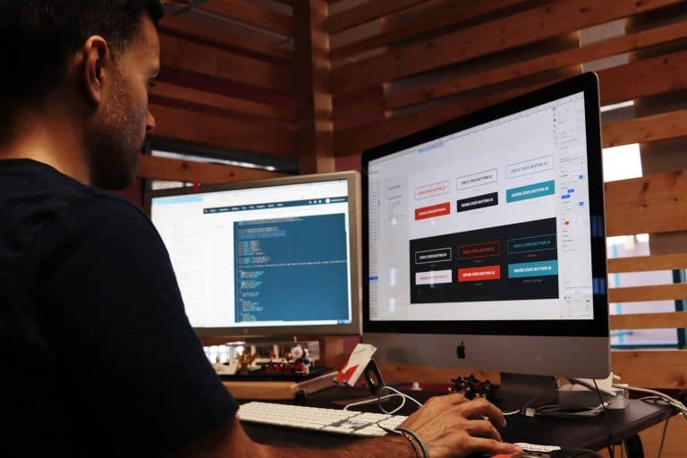 man looking at two computer monitors